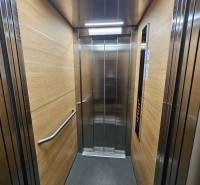 A lift belseje fa dekorációs panelekkel és rozsdamentes acél elemekkel.