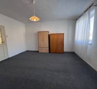 Szoba szőnyegpadlóval, fehér falakkal, két szekrénnyel és nagy ablakkal.