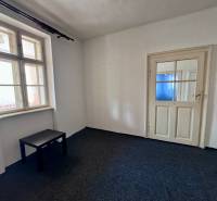 Sötét asztallal, ablakkal és fehér ajtókkal rendelkező szoba egy családi házban.