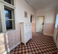 Egy családi ház folyosója csempézett padlóval és fehér bútorokkal.