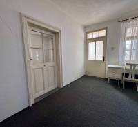 Családi ház belső tere szőnyeggel, íróasztallal és székkel, fehér falakkal.