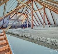 Padlás családi házban látható fa gerendákkal és lépcsővel.