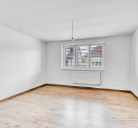 Üres szoba egy családi házban, fa dekorációjú padlóval és fehér falakkal.