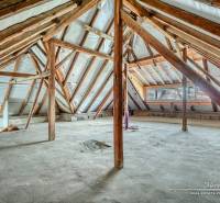 Családi ház padlása fa gerendákkal és nyers padlóval.