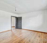 Szoba egy családi házban fehér falakkal és fa dekorációjú padlóval.