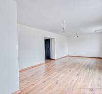 Tágas szoba egy családi házban, fa dekorációjú padlóval és fehér falakkal.