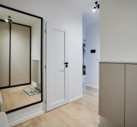 2 szobás lakás folyosója fa dekorációs padlóval és nagy tükörrel.