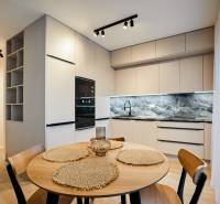 A kétszobás lakás konyhája kerek asztallal és fa mintázatú padlóval.