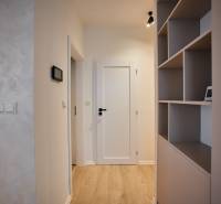 Folyosó egy 2 szobás lakásban polcos fallal és fa dekorációjú padlóval.