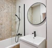 Fürdőszoba káddal, kerek tükörrel és modern mosdóval egy kétszobás lakásban.