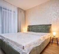 Hálószoba egy kétszobás lakásban ággyal, lámpával és fa dekorációjú padlóval.