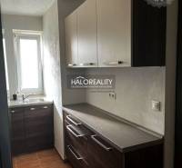 Konyha egy háromszobás lakásban sötét szekrényekkel és ablakkal.