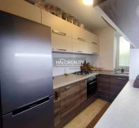 Konyha egy háromszobás lakásban, fa dekor padlóval és modern készülékekkel.