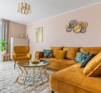 Nappali egy családi házban mustársárga kanapéval és fa dekorációjú padlón lévő asztallal.