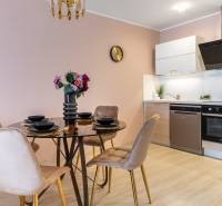 Ebédlő kerek asztallal és konyhapulttal egy családi házban, fa dekoros padlóval.