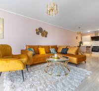 Nappali egy 4 szobás lakásban kényelmes kanapéval és fa dekorációjú padlóval.