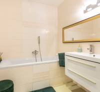 Fürdőszoba tükörrel, káddal és mosdóval egy családi házban, világos csempékkel.