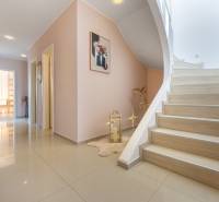 Családi ház folyosója járólappal, lépcsővel és dekorációkkal a falakon.