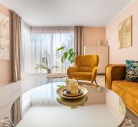 Családi ház nappalija kényelmes fotelekkel, dekoratív növényekkel és fa mintázatú padlóval.