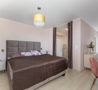 Hálószoba családi házban nagy ággyal, gardróbbal és fa dekorációjú padlóval.