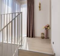 Családi ház belső tere fa dekor padlóval, függönyökkel és dekoratív világítással.