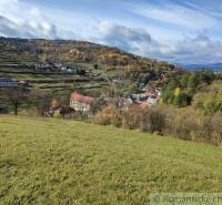 Ősz a Hlboké nad Váhom kertekben, szétszórt házakkal és színes fákkal.