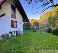 A szolosi ház külső része zöld gyep és fák által körülvéve.