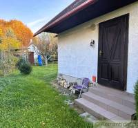 Ház Sološnicában gyepes udvarral és fákkal a színes őszi tájban.