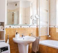 Fürdőszoba egy háromszobás lakásban mosdóval, káddal, mosógéppel és törölközőszárítóval.