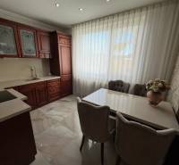 Konyha sötét szekrényekkel, fehér függönyökkel és virágos dekorációval egy családi házban.