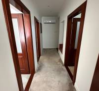 Egy családi ház folyosója fehér falakkal, szőnyeggel és fa ajtókeretekkel.