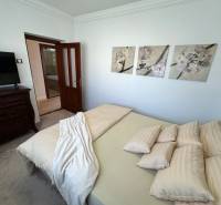 Családi ház hálószobája dekoratív képekkel a falon, kárpitozott bútorokkal és ajtókkal.