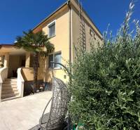 Családi ház Komáromban terasszal, kerti székkel és pálmafával az udvaron.