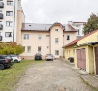 Épület a Zsolnai Pozsonyi utcában, autókkal és garázsokkal körülvéve, irodáknak alkalmas.