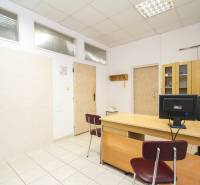 Irodák íróasztallal, székkel, számítógéppel és szekrénnyel világos kerámia padlón.