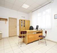 Iroda fa bútorokkal, számítógéppel és dekorációkkal a falakon, csempe a padlón.