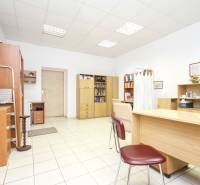 Irodák fehér falakkal, fa bútorokkal és kerámia padlóval.