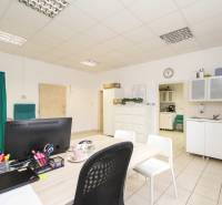 Iroda bútorokkal, számítógéppel és konyhával, a padlón csempék vannak.