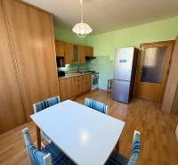 Konyha egy egyszobás lakásban, fa dekoros padlóval és étkezőasztallal.