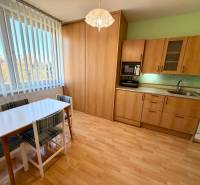 Konyha egy egyszobás lakásban fa dekor padlóval és étkezőasztallal.