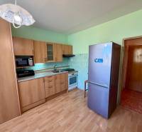 Konyhapult mikrohullámú sütővel és hűtőszekrénnyel az egyszobás lakásban, fa hatású padlóval.