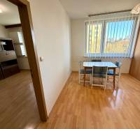 Étkezőasztal székekkel egy egyszobás lakásban, fa mintázatú padlóval.