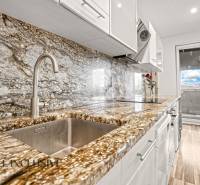 Konyha kő munkalappal és fa dekorációjú padlóval egy háromszobás lakásban.