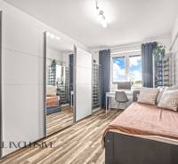 Szoba tükrös szekrénnyel, íróasztallal és fa dekorációjú padlóval egy háromszobás lakásban.