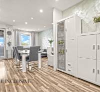 Világos belső tér háromszobás lakásban, fa dekorációjú padlóval és fehér bútorokkal.