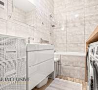 Fürdőszoba egy háromszobás lakásban káddal, csempékkel és fa dekoros padlóval.