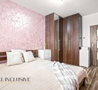 Hálószoba ággyal, szekrénnyel és fa dekorációjú padlóval egy háromszobás lakásban.