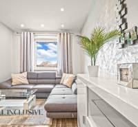 Nappali szürke kanapéval, üvegasztallal és fa dekorációjú padlóval.