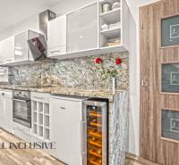 Konyha egy 3 szobás lakásban fa dekor padlóval és márvány munkalappal.