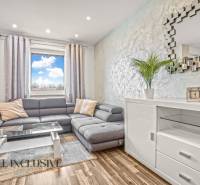 Nappali egy háromszobás lakásban kényelmes kanapéval és fa dekorációjú padlóval.